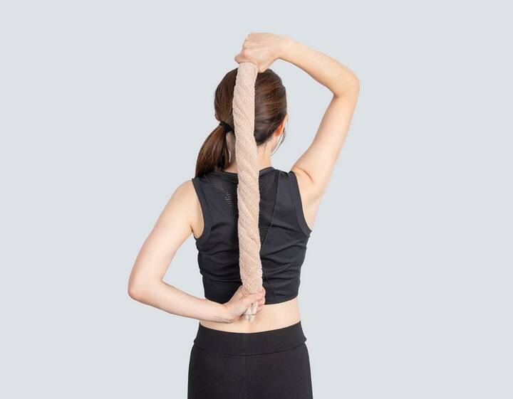 背中側に手を回して、ねじったフェイスタオルを持つ