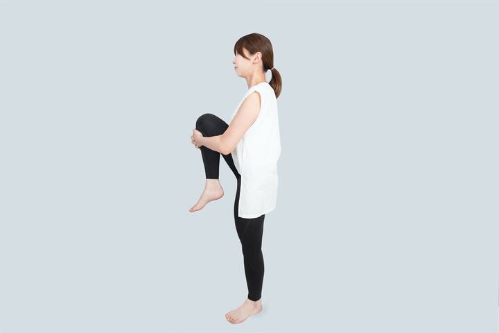 まっすぐに立ったまま、足を手で抱えるように引き寄せる